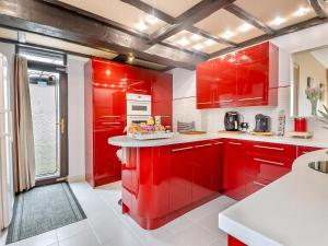 a red kitchen with white counters and red cabinets at Beachside House in Scratby