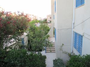a building with blue doors and bushes next to a building at Maison Karim in Nabeul