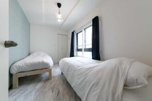 a white bedroom with a bed and a window at GaiarS8 in Sapporo