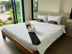 Dos patitos de goma están sentados en una cama. en Baan Home Resort, en Kalasin