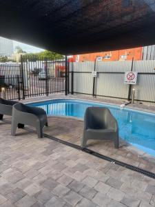 a swimming pool with two chairs next to it at Darwin City Escapes - 1 bedroom unit in Darwin
