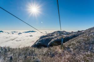 a ski lift going over a mountain with clouds at Zhangjiajie Jijiehao Inn in Zhangjiajie