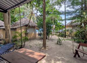 a swing in front of two buildings with trees at Dreamy beachfront bungalow in Baan Tai