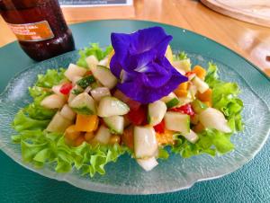 a salad on a blue plate with a flower on it at travis homestay in Siquijor