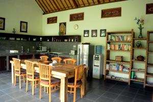 a kitchen with a wooden table and chairs and a refrigerator at Villa Mangga in Ubud