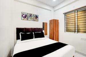 a bedroom with a black and white bed and a window at Hotel O Mannat in Indore