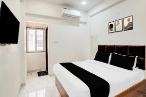 a white bedroom with a black and white bed at Hotel O Mannat in Indore