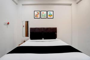 a bedroom with a large white bed with two pictures on the wall at Hotel O Mannat in Indore +25 photos