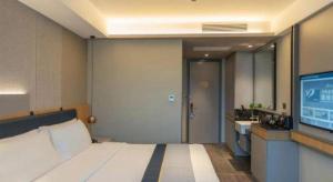a hotel room with a bed and a flat screen tv at Home Inn Kunming Baita Road in Kunming