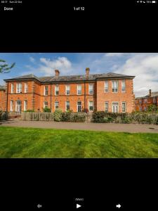 un gran edificio de ladrillo rojo con un patio de césped en Lovely Bed and Breakfast in Chichester nr Festival Theatre City Centre and Goodwood Top Floor Spacious Kingsize Ensuite, en Lavant