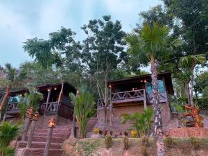a house with palm trees in front of it at Lake View Fishing Camp in Kaeng Krachan