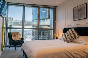 a bedroom with a bed and a chair and a large window at Riverside Reverie French Luxury at BNE Casino in Brisbane