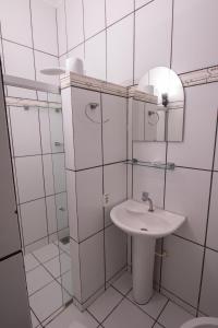 a white bathroom with a sink and a mirror at Pousada do Mineiro in Trancoso