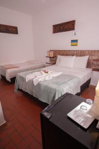two beds in a hotel room with a desk at Pousada do Mineiro in Trancoso