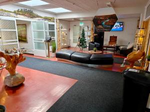 a living room with a black leather couch and a tv at Hostel Aurora in Kuusamo