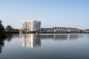 卡纳克Thalazur Carnac的一座白色的大楼倒映在水中