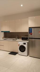 a kitchen with a washing machine and a refrigerator at Quill Residence- Minimalist Urban Condo by Azmila in Kuala Lumpur