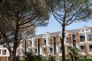 Un gran edificio blanco con árboles en primer plano. en Thalazur Carnac, en Carnac