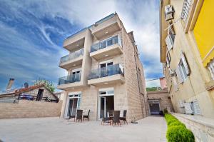 a building with chairs and a table in front of it at Apartments Bojana in Tivat