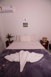a white bed with a towel laying on it at Pousada do Mineiro in Trancoso