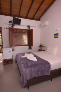 a bedroom with a bed with a tv on the wall at Pousada do Mineiro in Trancoso
