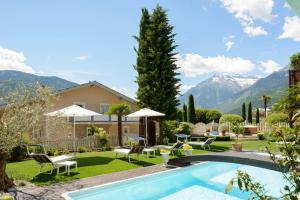 a villa with a swimming pool and mountains at Hotel Alpenhof in Tirolo