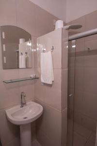 a white bathroom with a sink and a mirror at Pousada do Mineiro in Trancoso