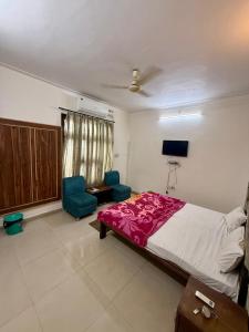 a bedroom with a bed and two blue chairs at KRISHNAM GUEST HOUSE in Gwalior