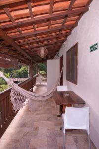 a porch with a hammock and a table and chairs at Pousada do Mineiro in Trancoso