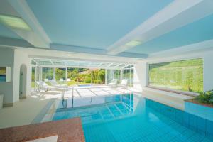 a swimming pool in a house with a large window at Hotel Mühle Mayer in Termeno