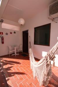 a hammock in a room with a television and a table at Pousada do Mineiro in Trancoso