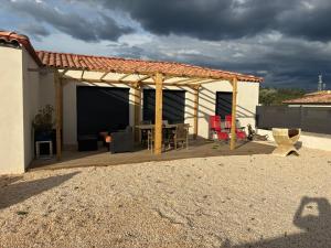 a pergola with a table and chairs on a patio at villa de vacances in Cessenon