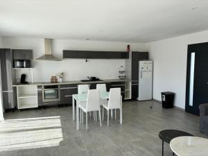 a kitchen with a table and white chairs in it at villa de vacances in Cessenon
