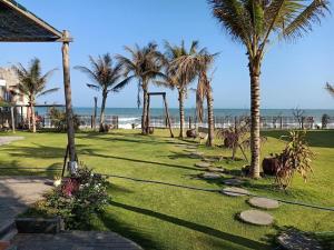 a park with palm trees and a swing and the ocean at Homestay Lac Long Quan by the Sea in Bình Sum