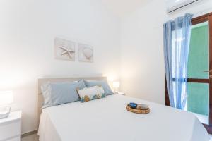 a white bedroom with a white bed and a window at Casa Il Nido, 250m to beach in Fort Village