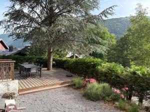 a wooden deck with a table and chairs under a tree at Chalet Yuki in Morzine