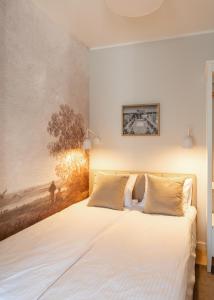 a bedroom with a white bed with a painting on the wall at Apartament Wejhera II in Puck