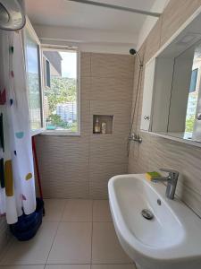 a white bathroom with a sink and a window at Liza's apartments in Shëngjin