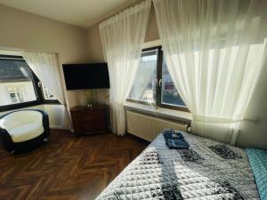 ein Schlafzimmer mit einem Bett und einem Stuhl und Fenstern in der Unterkunft Ferienwohnung-Oberstein im Zentrum in Idar-Oberstein