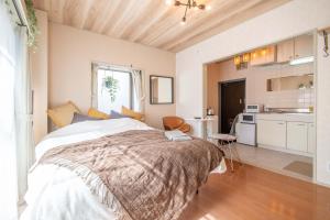 a bedroom with a large bed and a kitchen at Lazurite GUESTHOUSE Pear Field in Inagi
