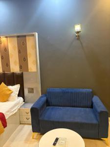 Una sala de estar con un sofá azul y una cama. en Premium luxury Stay, en Ghaziabad