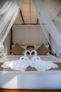 two white swans making a heart on a bed at The Wild Side Cottage in Udawalawe