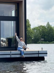 Eine Frau, die auf einem Steg im Wasser sitzt. in der Unterkunft Winter Getaway Houseboat Stay Romantic in Monnickendam