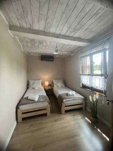 two beds in a room with two windows at Dom ARCHITEKTA in Stoki Duże