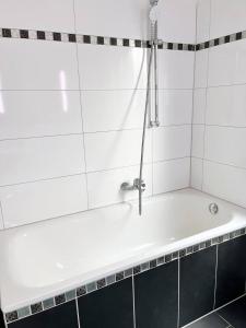 a bath tub with a shower in a bathroom at Stilvolleauszeit mit Garten - 15 min bis Köln in Hürth +3 photos