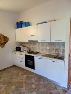 a kitchen with white cabinets and a sink at Capo Ceraso Family Resort in Costa Corallina