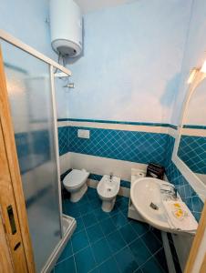 a blue bathroom with a toilet and a sink at Capo Ceraso Family Resort in Costa Corallina