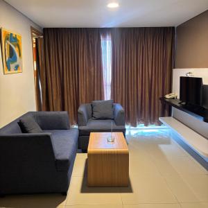 a living room with two couches and a coffee table at Kyriad Haka Makassar in Makassar