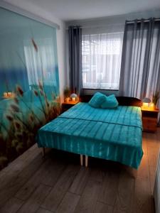 a bedroom with a bed with a blue comforter at Apartament z klimatyzacją in Kąty Rybackie