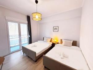 アテネにあるAlimos Apartment near Edem Beach and the Sea with 2 Bedroomの大きな窓のある部屋にベッドが2つある